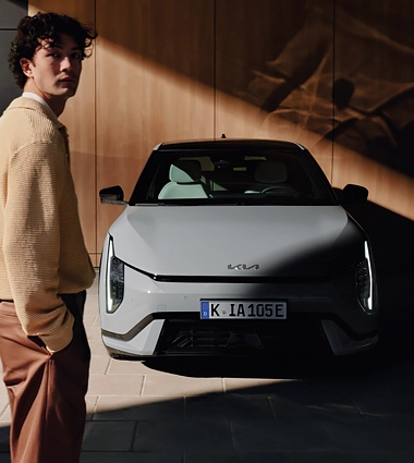Mann steht neben einem grauen Kia EV4