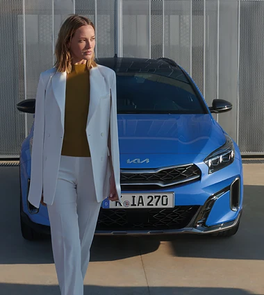 Frau steht vor einem blauen Kia XCeed
