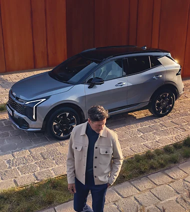 Mann steht neben einem grauen Kia Sportage