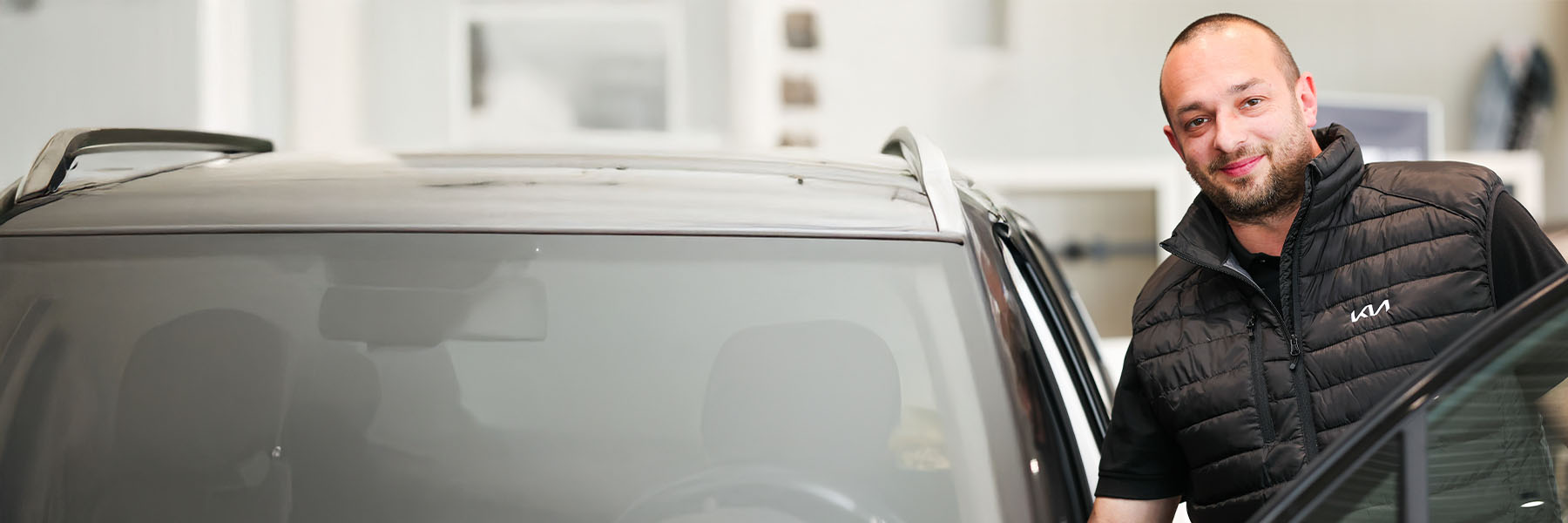 Verkaufsberater lehnt am Auto 