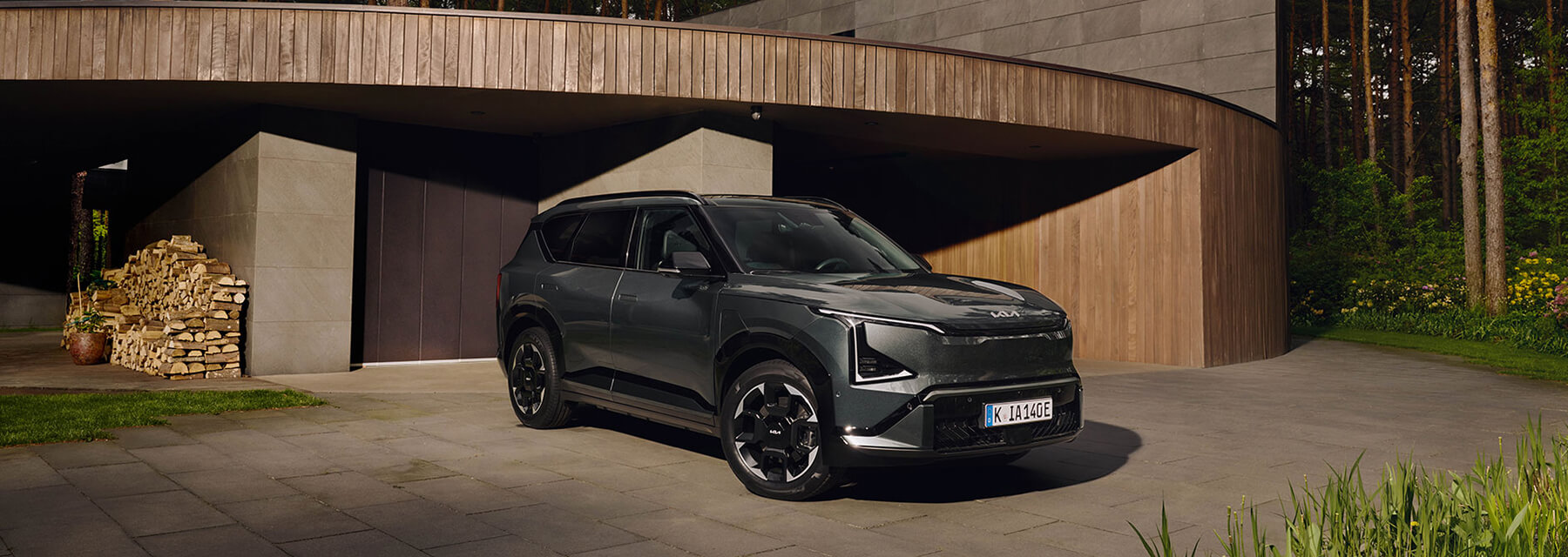 Kia EV5 seitlich von vorne vor der Garage eines Hauses