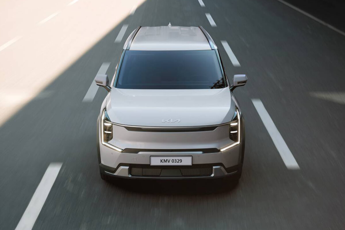 Man sieht den Kia EV9 von vorne, leicht von oben, auf einer Autobahn. 