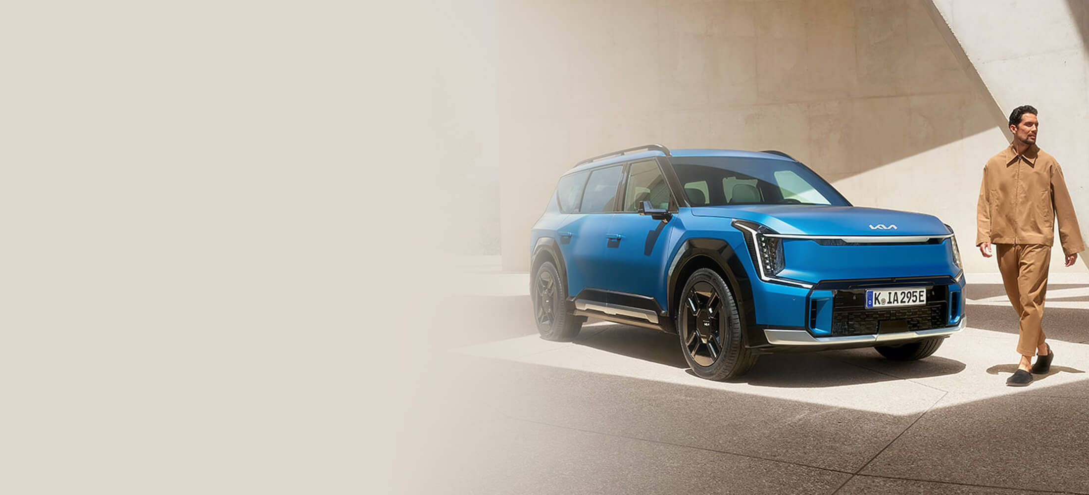 Kia EV9 GT-Line seitlich von vorne mit einer männlichen Person vor dem Fahrzeug.