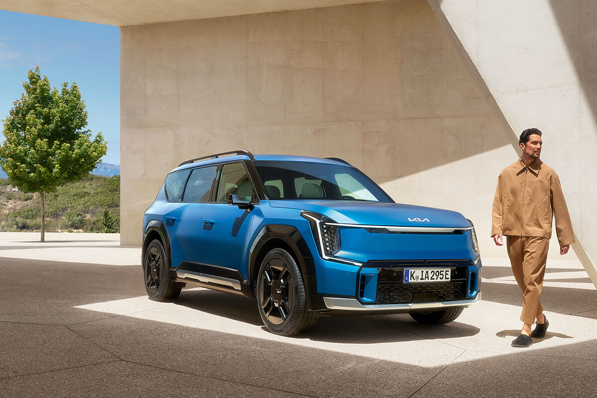 Kia EV9 GT-Line seitlich von vorne mit einer männlichen Person vor dem Fahrzeug.