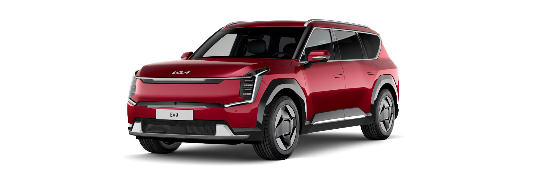 Kia EV9 GT-Line fährt auf einer Landstraße am Meer im Sonnenuntergang.