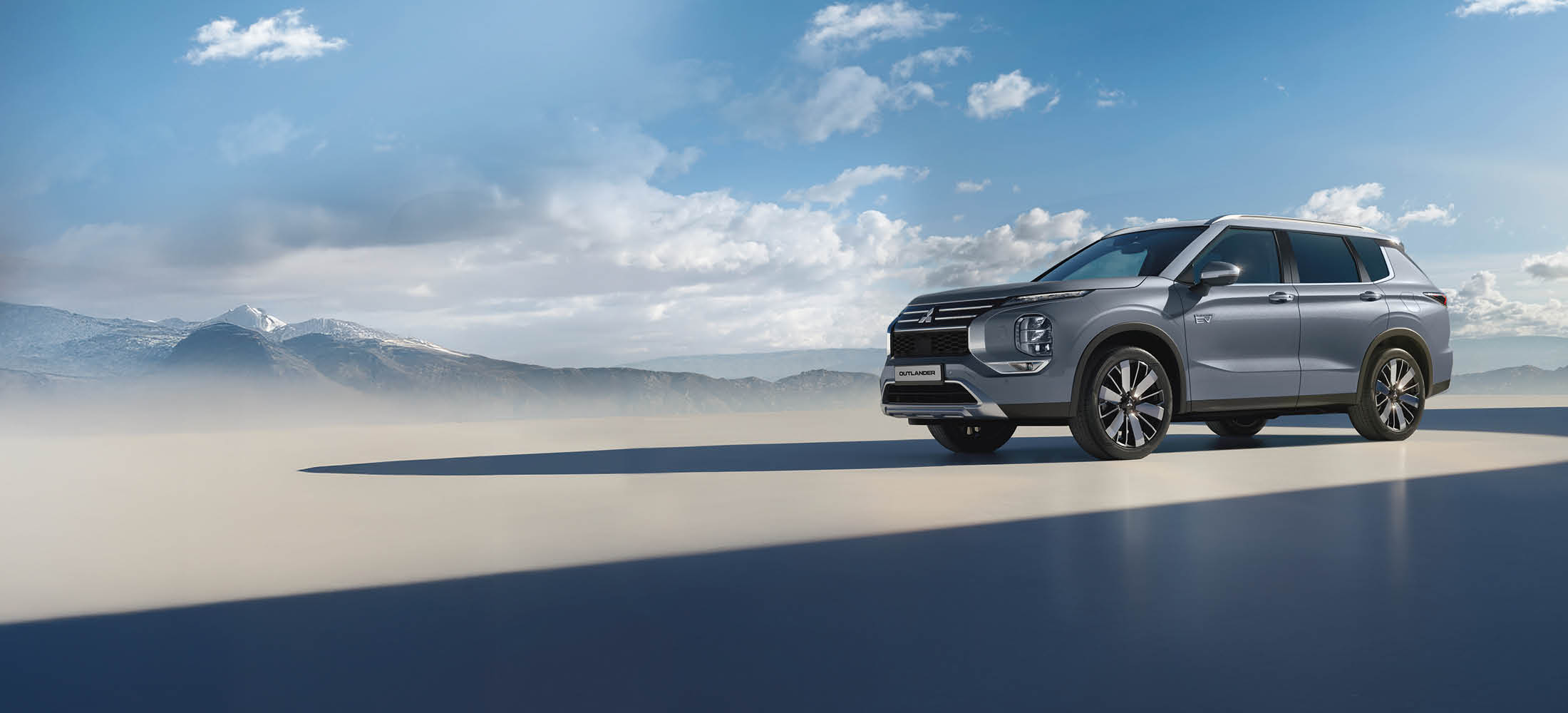 Outlander steht auf einer Plattform im Hintergrund blauer Himmel und Berglandschaft