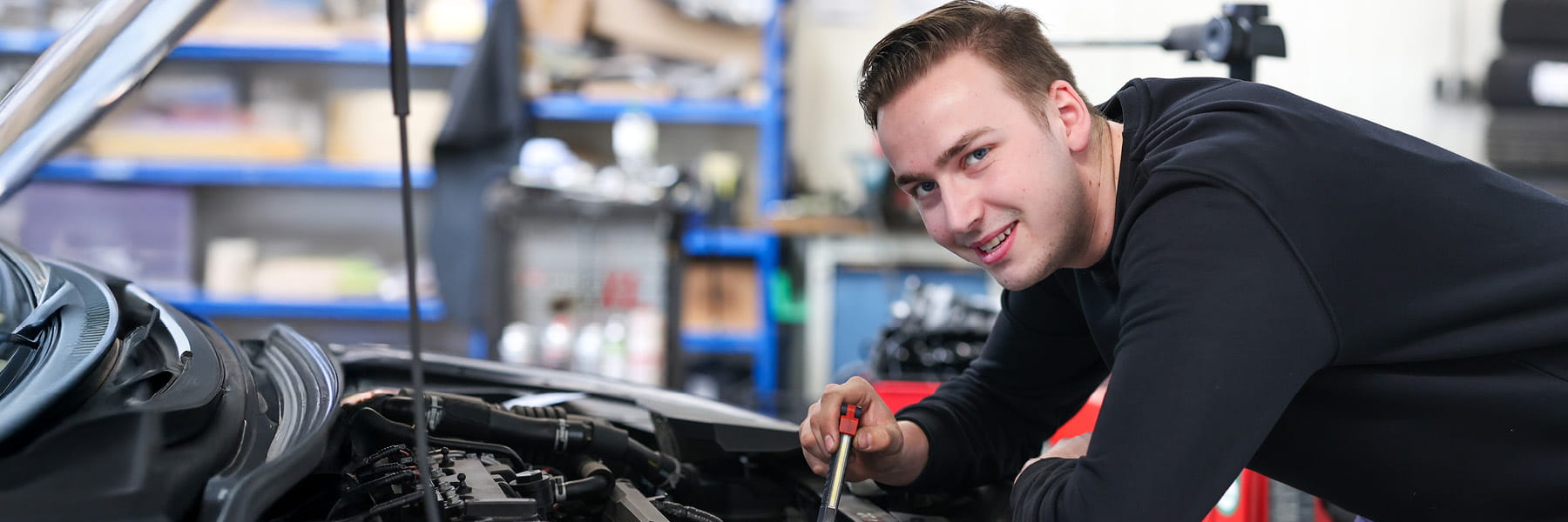 Mechatroniker lehnt an der Motorhaube